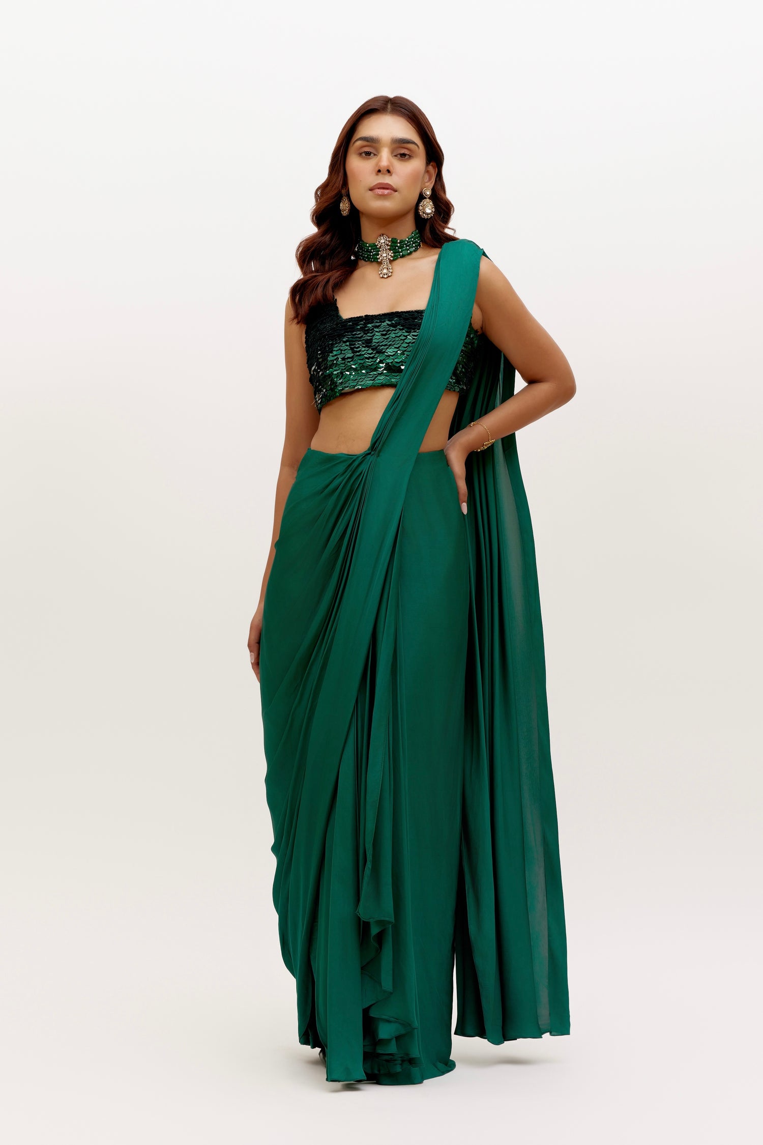 The Raya Drape Saree includes a sequin square-neck blouse and a silky, figure-flattering skirt with an attached drape in a deep, rich emerald color. The attached drape just has to be wrapped around you to complete the look in less than 5 seconds.
