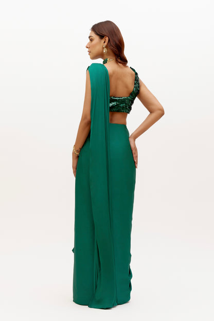 The Raya Drape Saree includes a sequin square-neck blouse and a silky, figure-flattering skirt with an attached drape in a deep, rich emerald color. The attached drape just has to be wrapped around you to complete the look in less than 5 seconds.