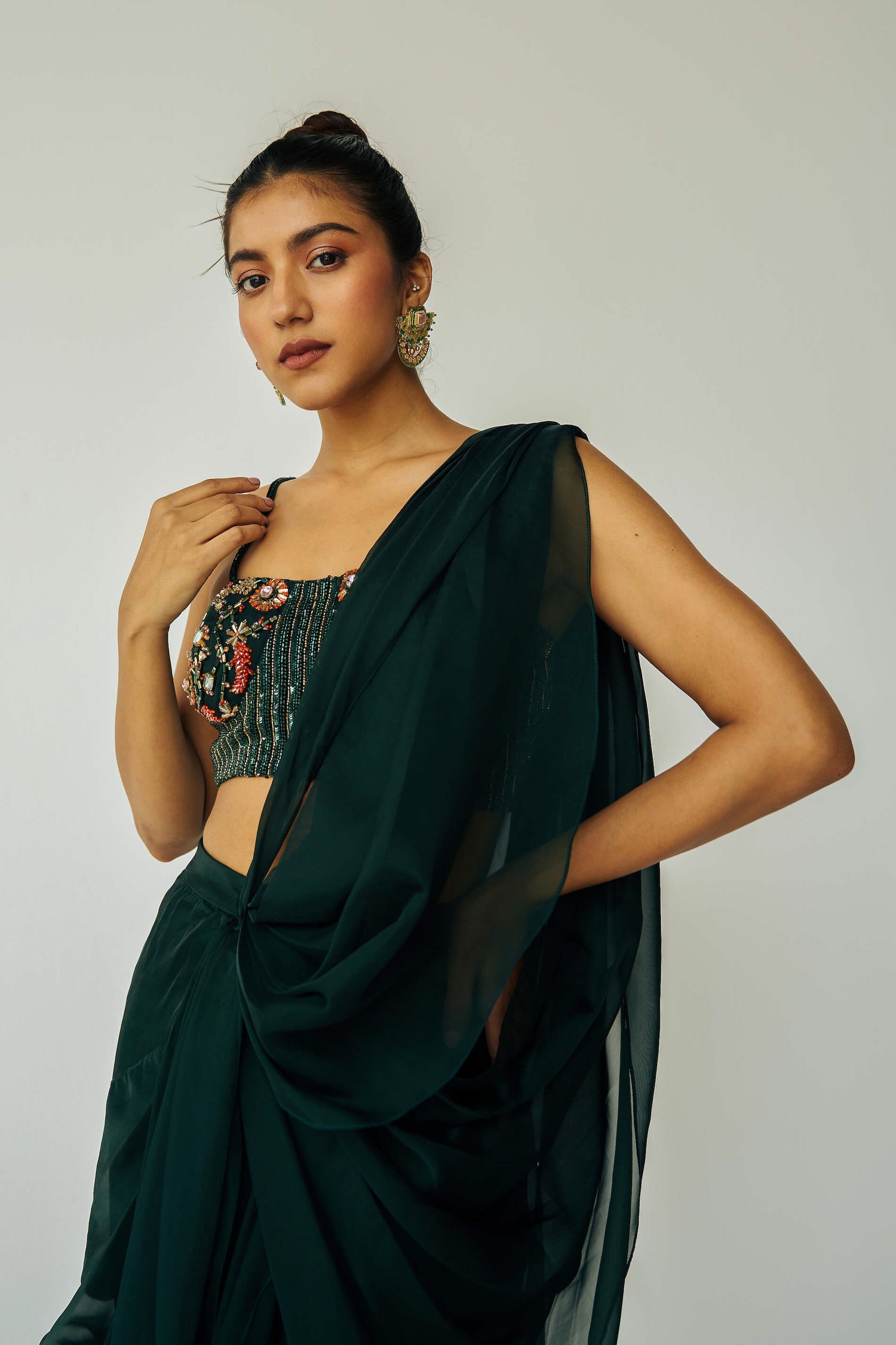 The Adya Drape Saree makes it easy to get the saree look without any pleating and features a shiny organaza skirt with an attached drape + a hand embroidered, bustier top.