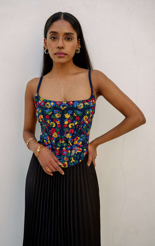 The Zinnia Top is a corset style with embroidered, multicolored flowers and adjustable straps. 