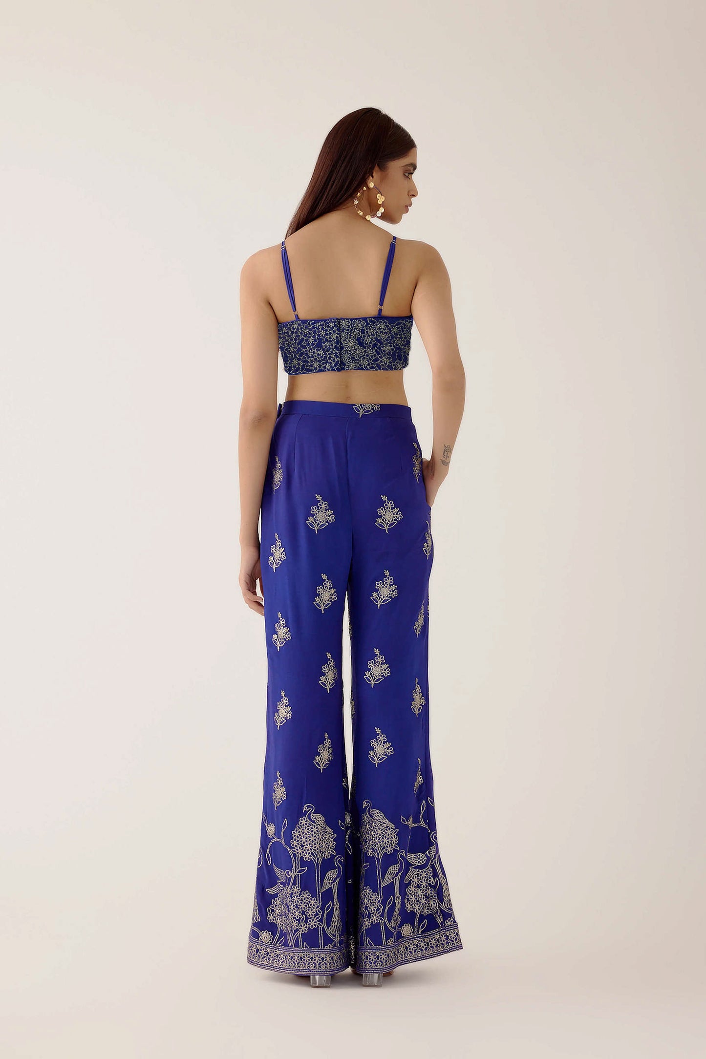 The embroidered Manali Set consists of a blue vest, bra top, and flared pants.