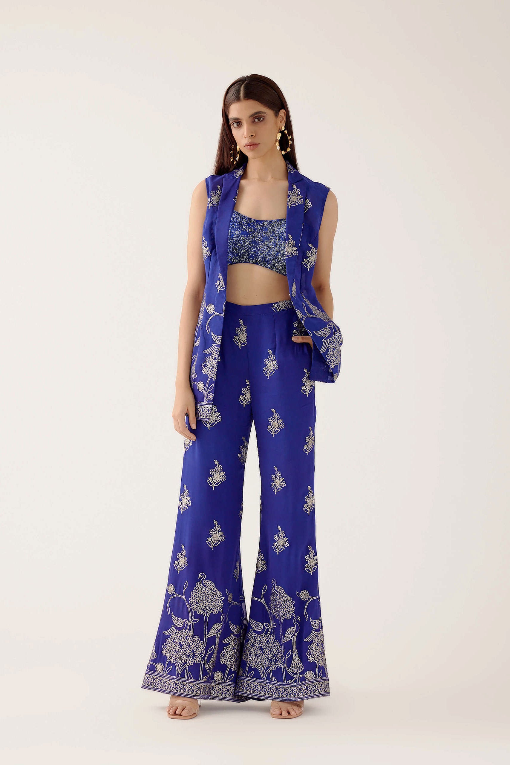 The embroidered Manali Set consists of a blue vest, bra top, and flared pants.