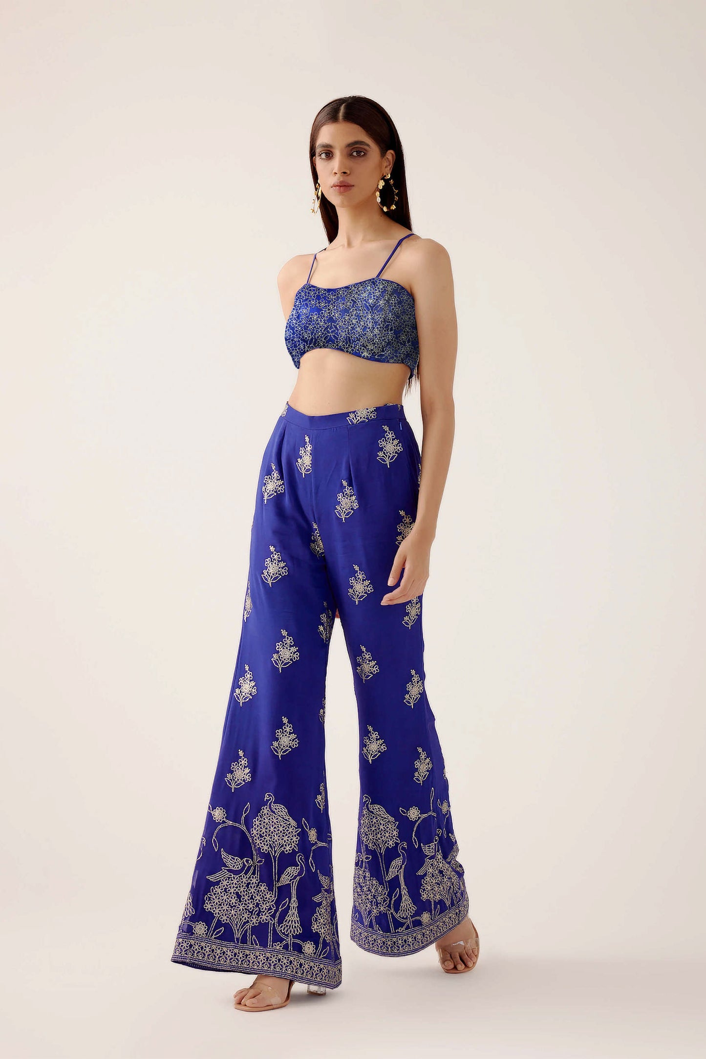 The embroidered Manali Set consists of a blue vest, bra top, and flared pants.