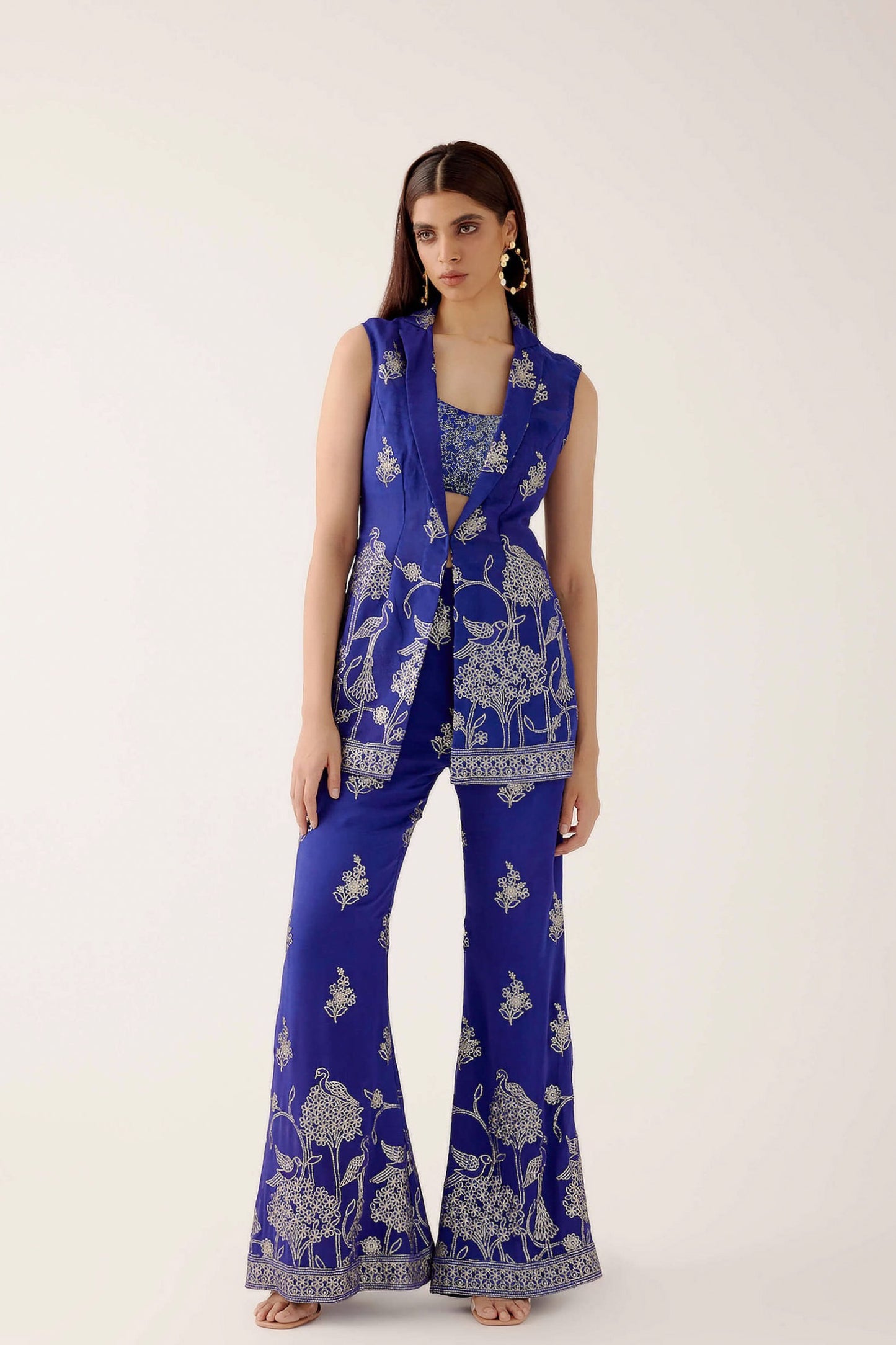 The embroidered Manali Set consists of a blue vest, bra top, and flared pants.