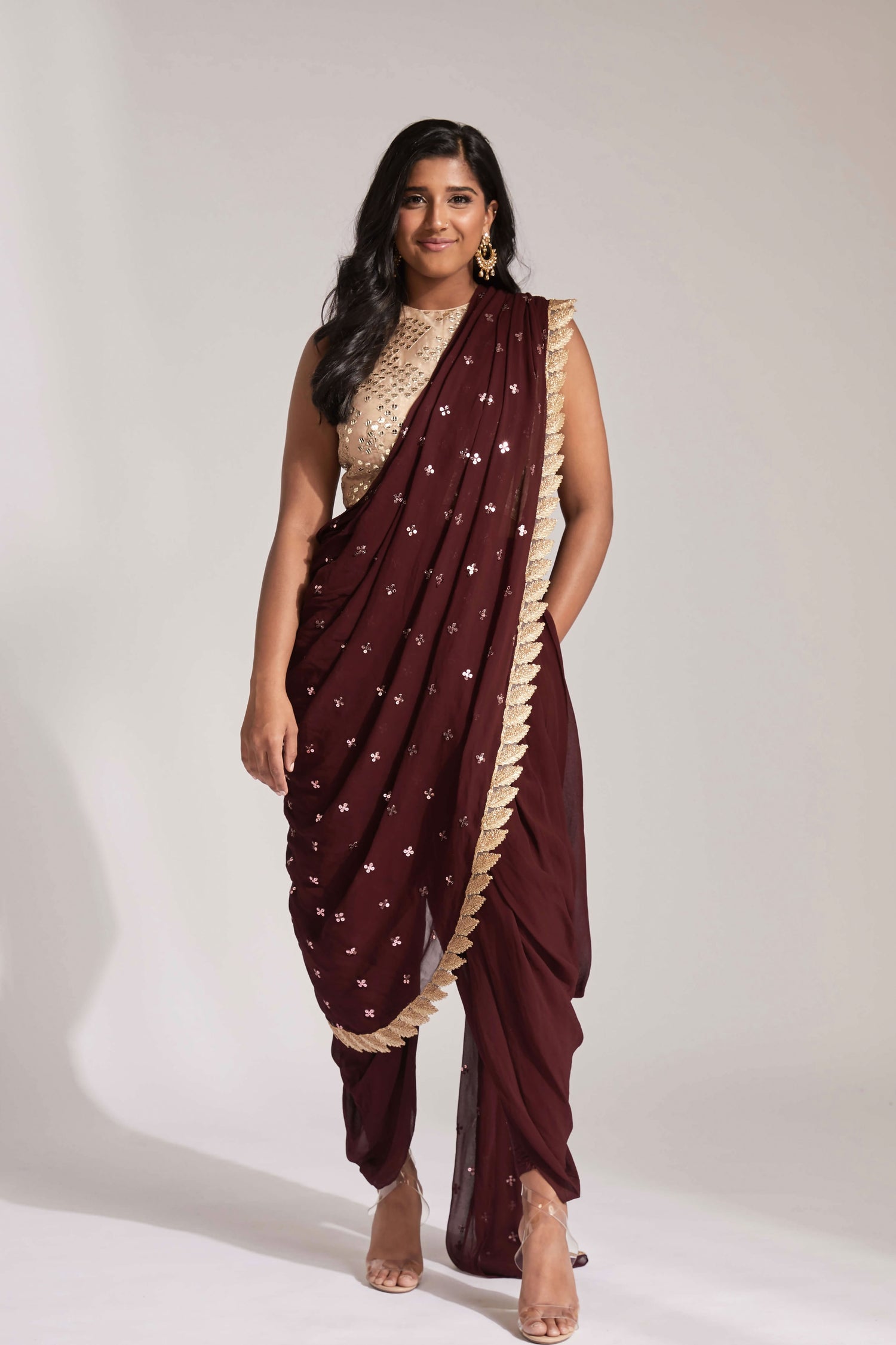 The Tara Dhoti takes the elegance of a saree's drape and combines it with the comfort of a dhoti pant. The booti-work drape is attached to the outfit and is paired with a mirror work blouse.