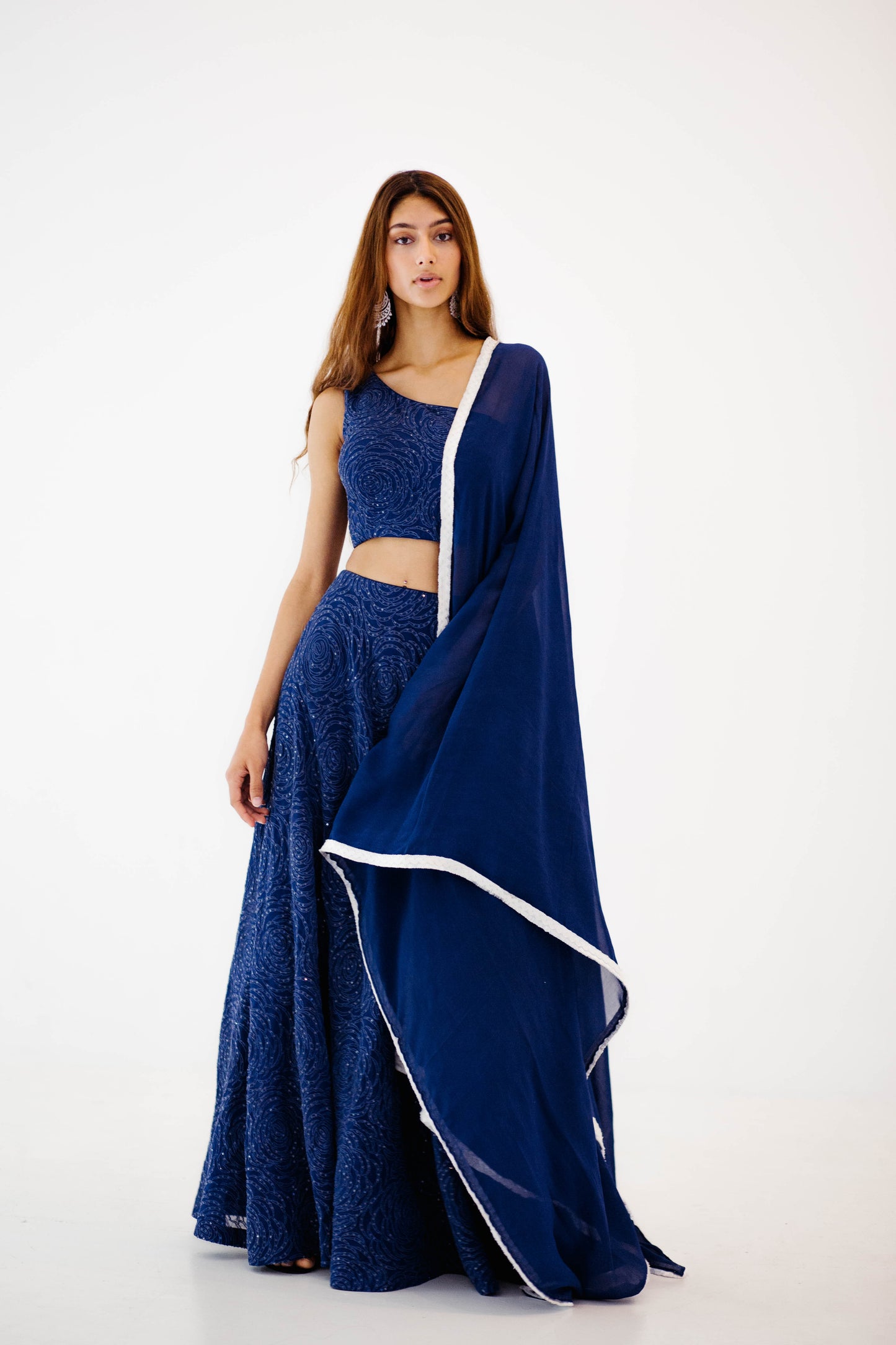 The Raz Lehenga has a dark blue georgette skirt with thread and sequin work in the shape of roses, featuring a one shoulder blouse, and is paired with a matching dupatta.